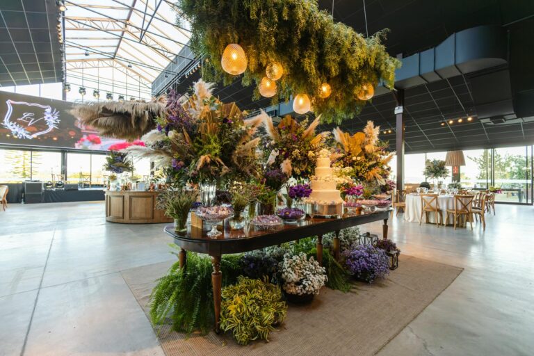 Beautifully arranged wedding venue with floral decor and wedding cake, set indoors.