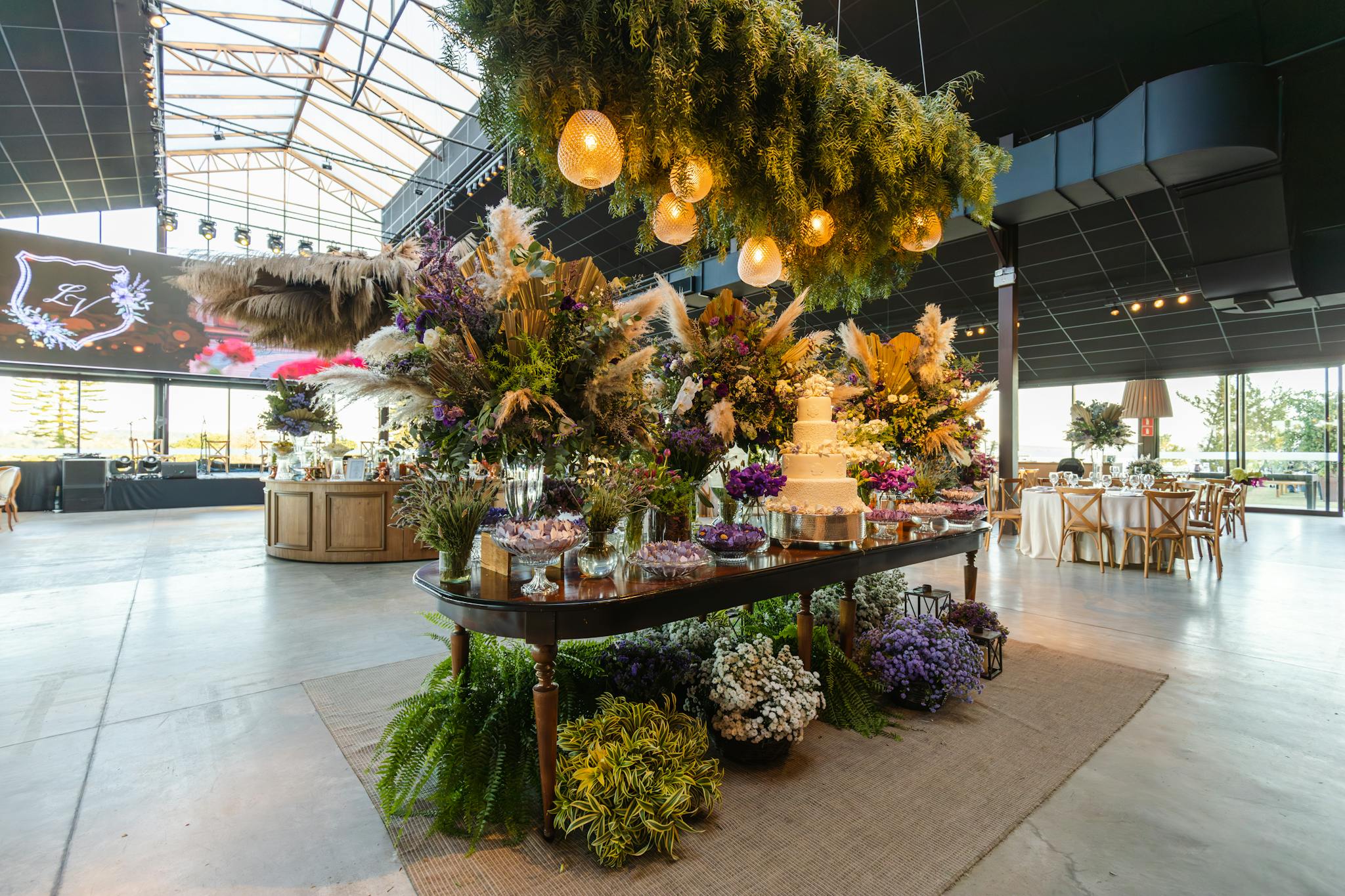 Beautifully arranged wedding venue with floral decor and wedding cake, set indoors.